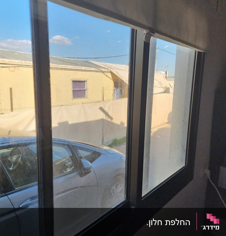 חלון זכוכית עם נוף חיצוני של רכב ובניין